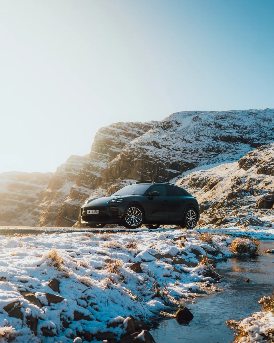 Porsche in a snowy mountain landscape beside a stream